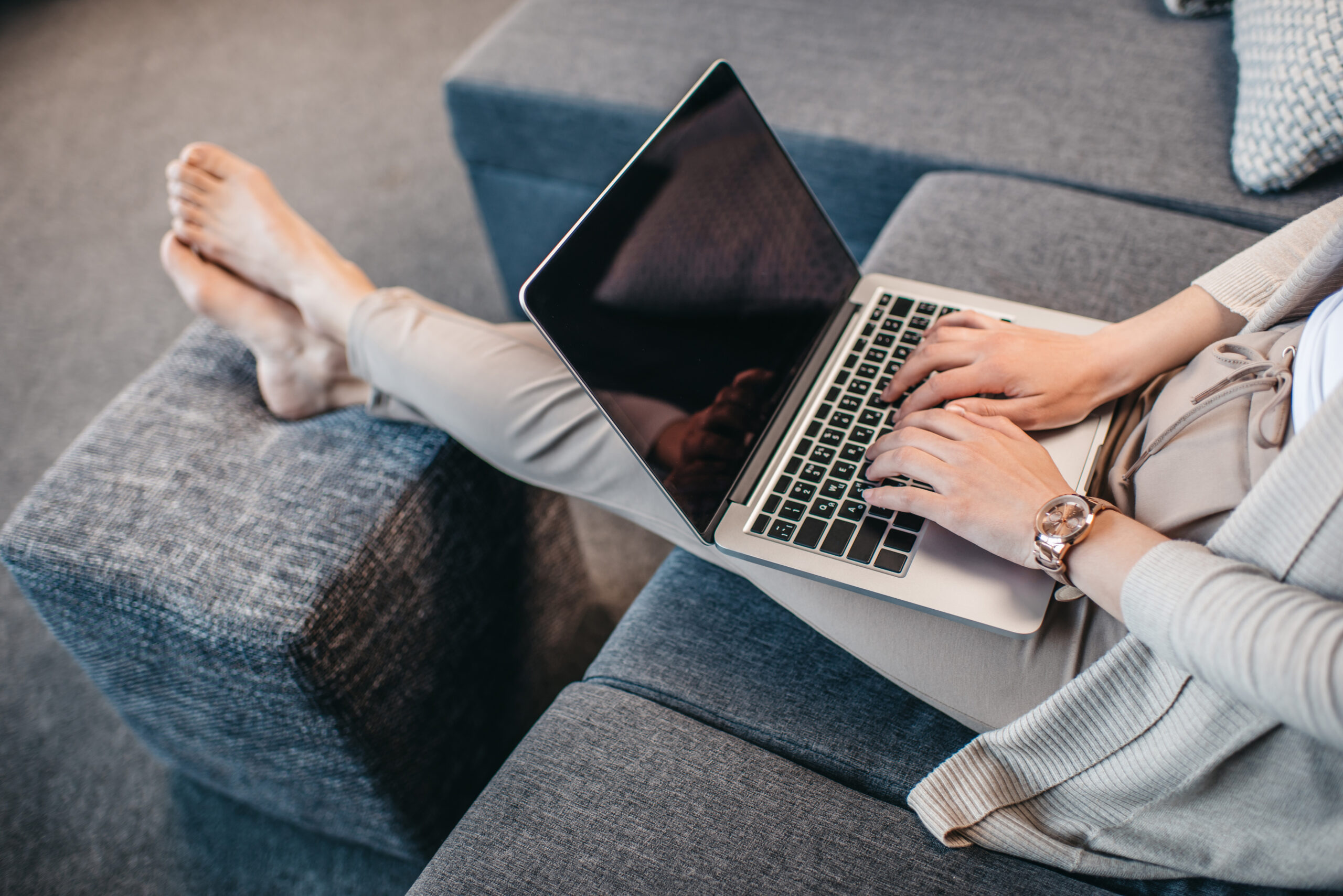 woman typing on her laptop while sitting on her couch working from home