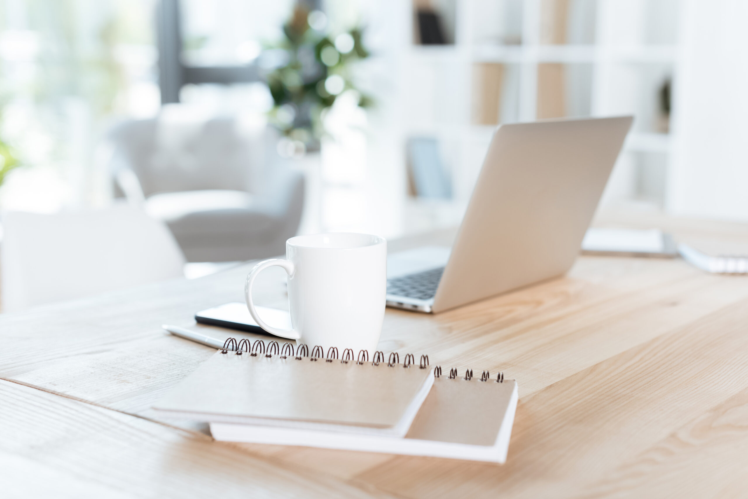 Laptop, coffee cup, and notebooks on a desk