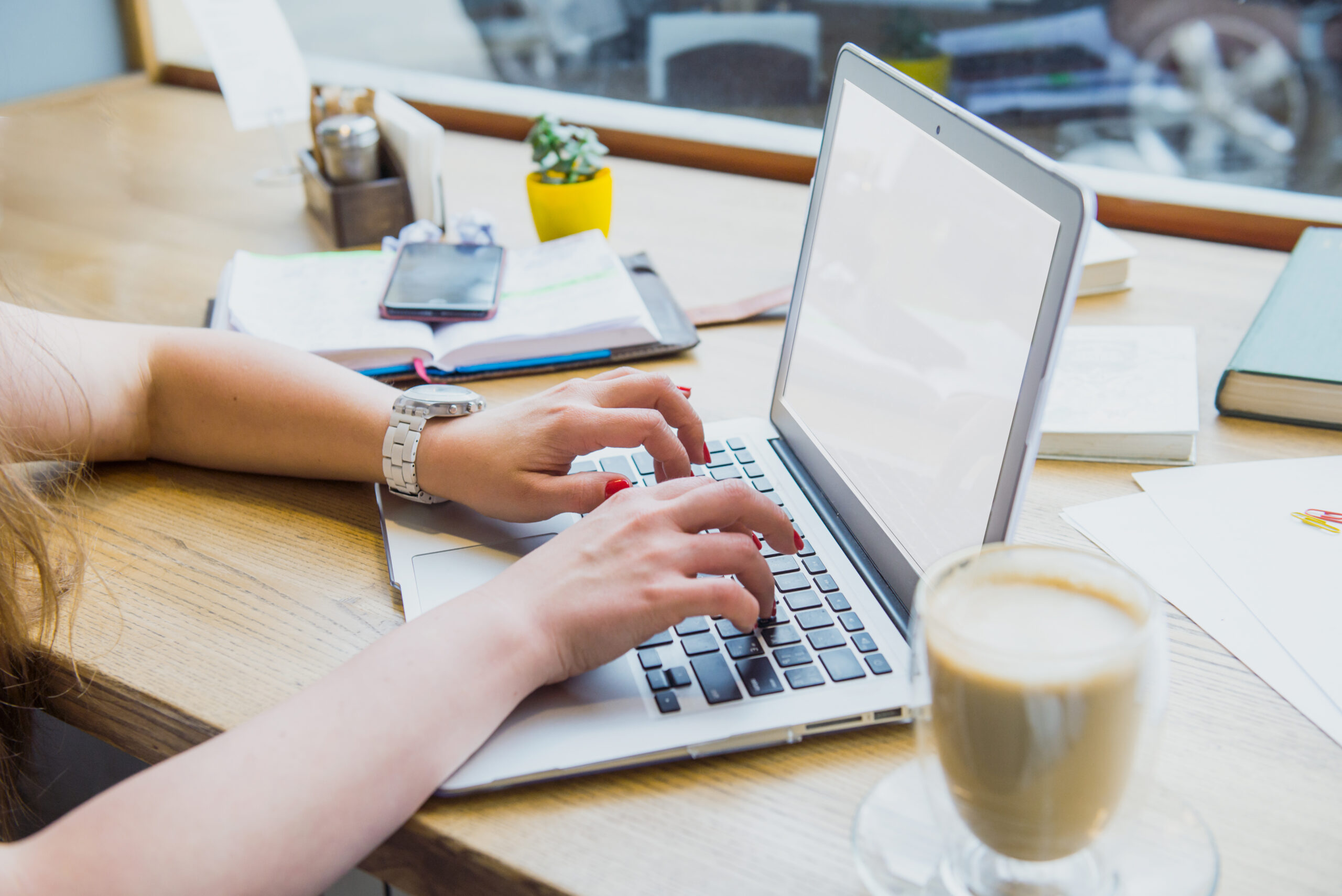 woman typing on a laptop with a cup of coffee